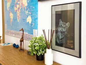 A framed picture of a cat, a small potted plant, a world map, and a giraffe figurine on a wooden table.