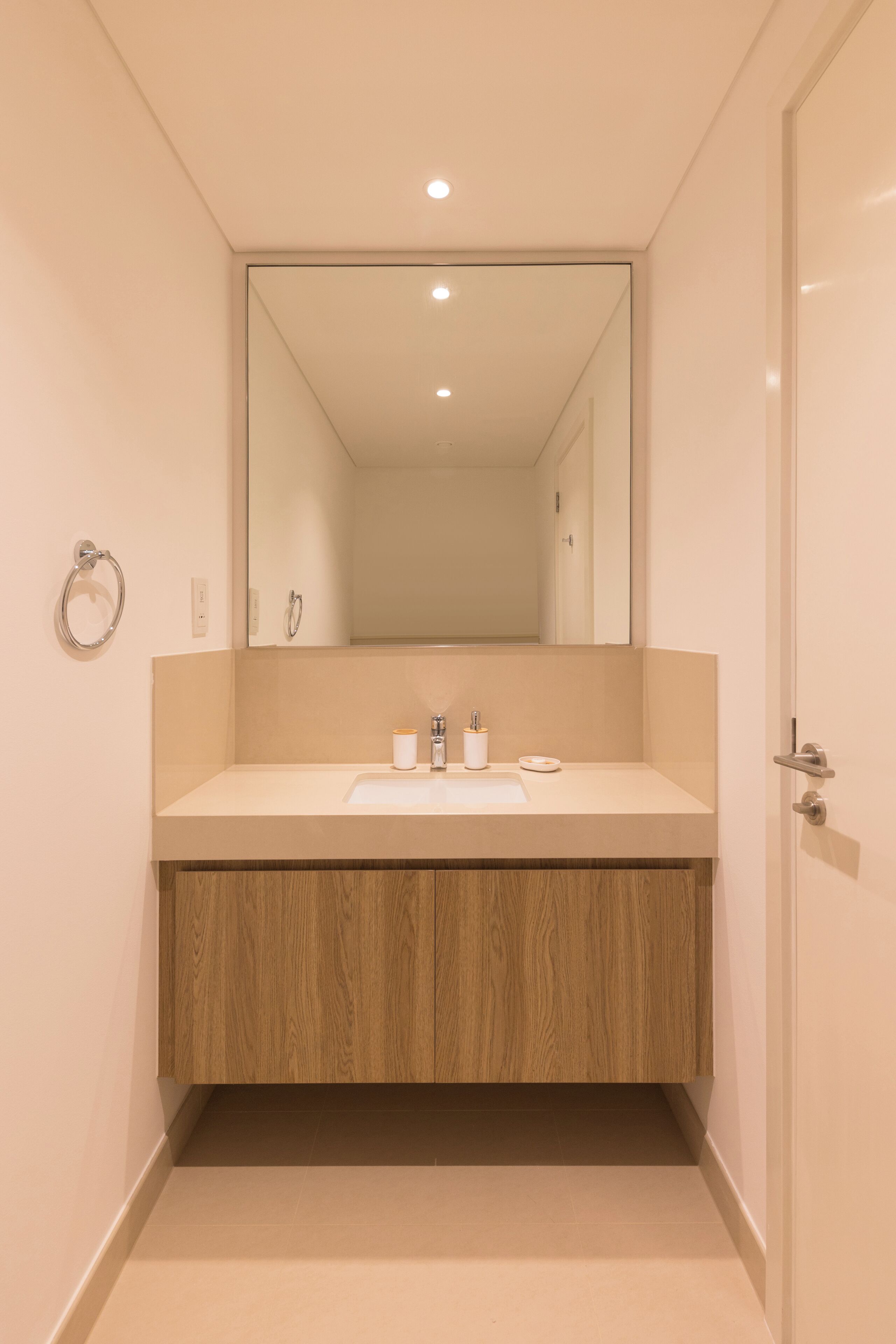 A modern bathroom with a wooden vanity, a large mirror, and a white sink.