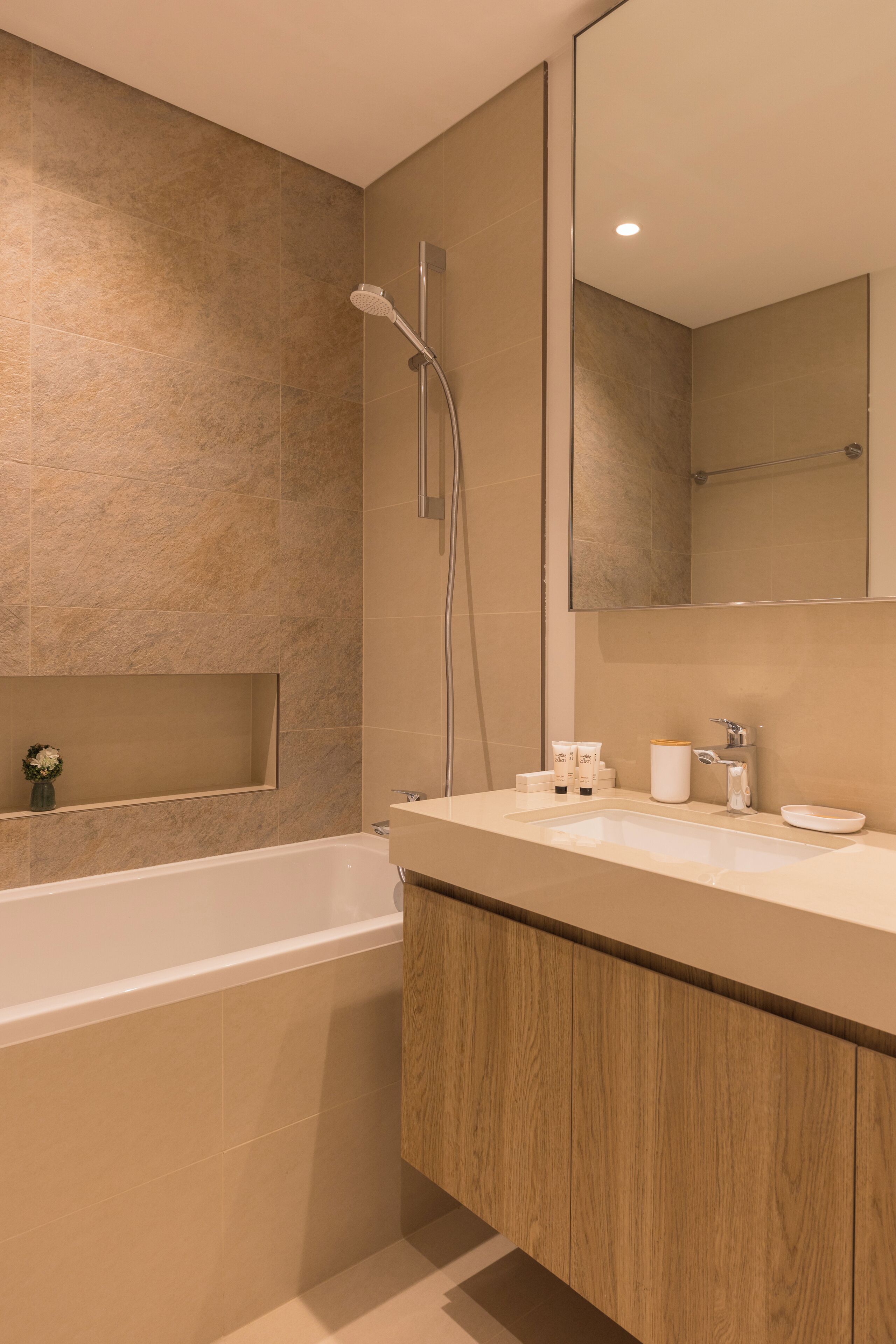 Une salle de bain moderne avec une baignoire, un grand miroir et un meuble-lavabo en bois.