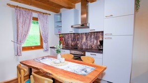 A compact kitchen with white cabinets, a wooden table, and a window with curtains.
