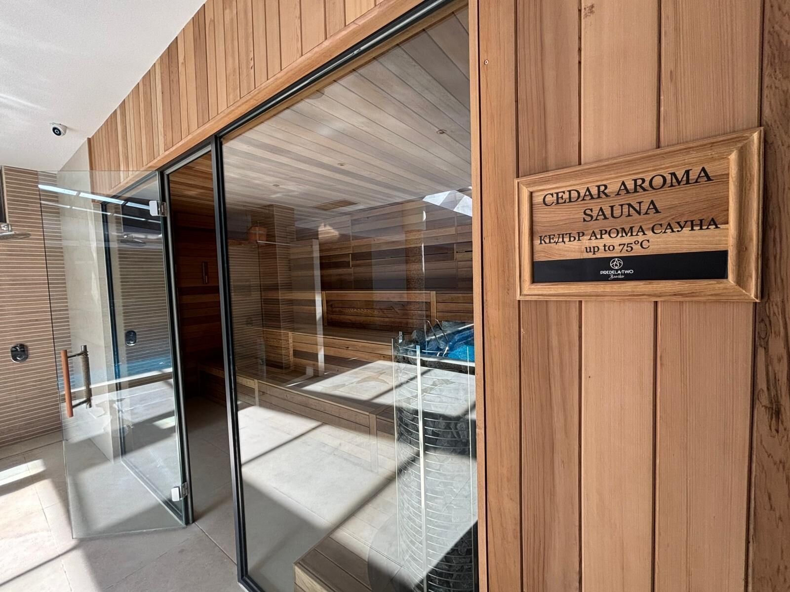 Un sauna aux effluves de cèdre, doté d’une porte en verre et d’un intérieur en bois.