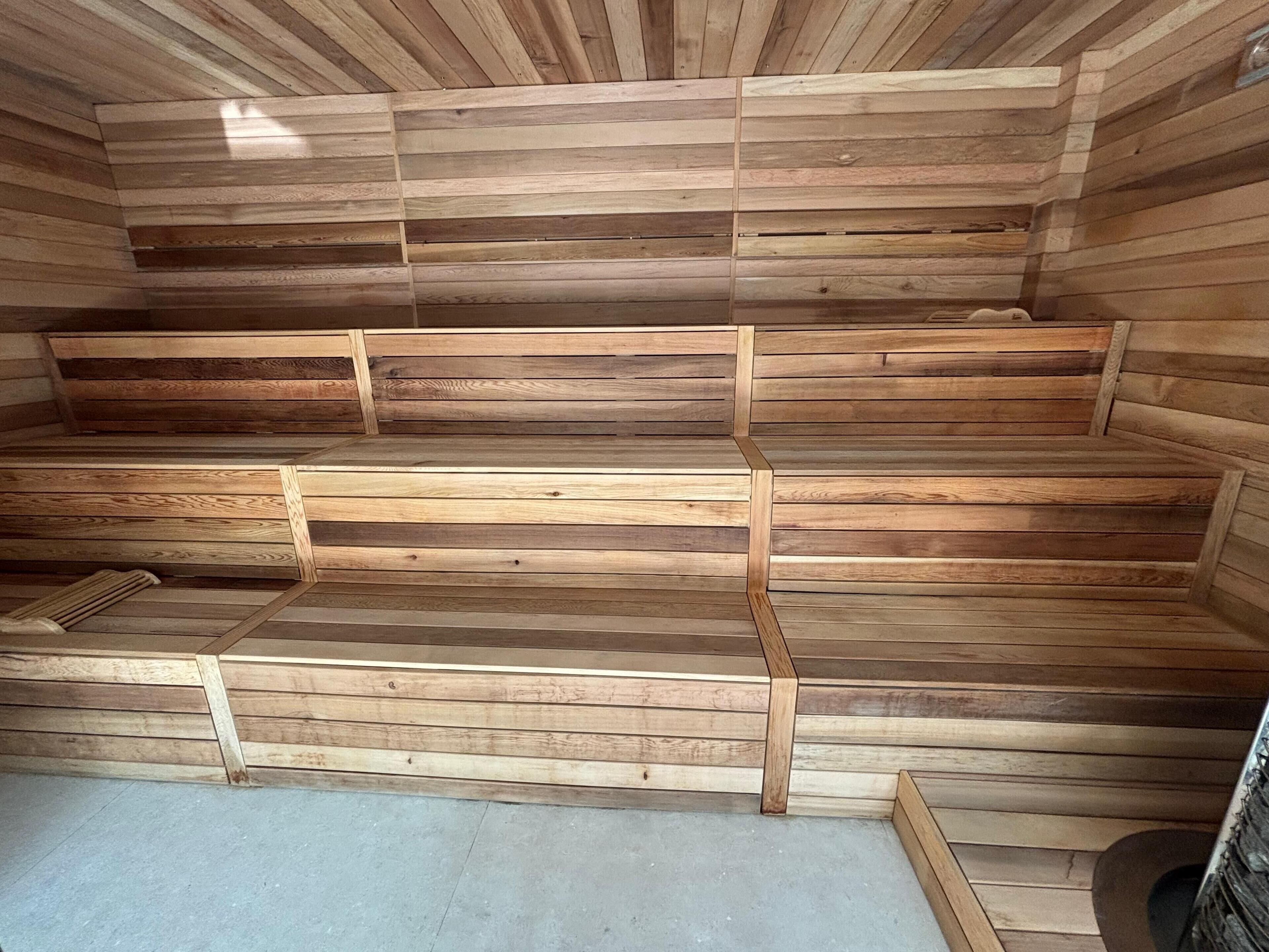 A sauna with wooden benches and a concrete floor.