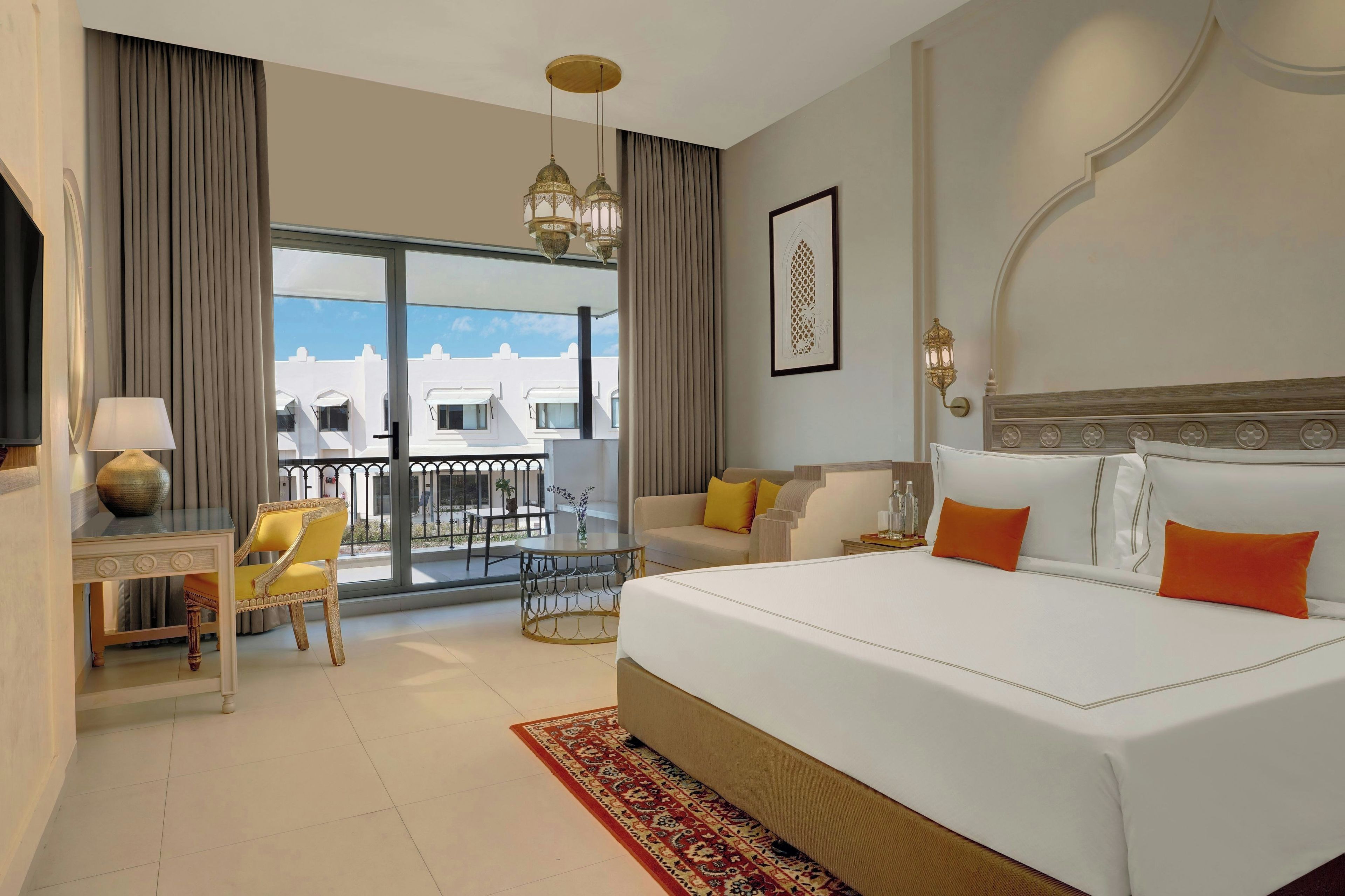 Camera d'albergo con un letto grande, un balcone vista panoramica, un tavolino con una lampada e un divano.