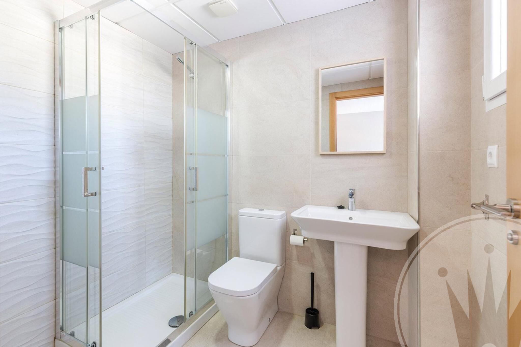 A modern bathroom with a glass shower enclosure, a white toilet, and a pedestal sink.