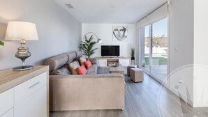A modern living room with a sofa, TV, and a large window.