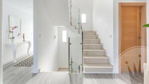 A modern interior with a staircase, a wooden door, and a white console table with a mirror and potted plant.