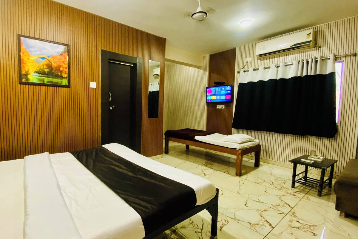A hotel room with a large bed, a wooden panel wall, a television, and a small table.