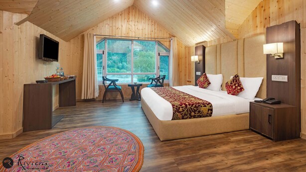 A wooden cabin bedroom with a large bed, a desk, and a TV. - Hotel Riviera By Mount view (Anantnag)