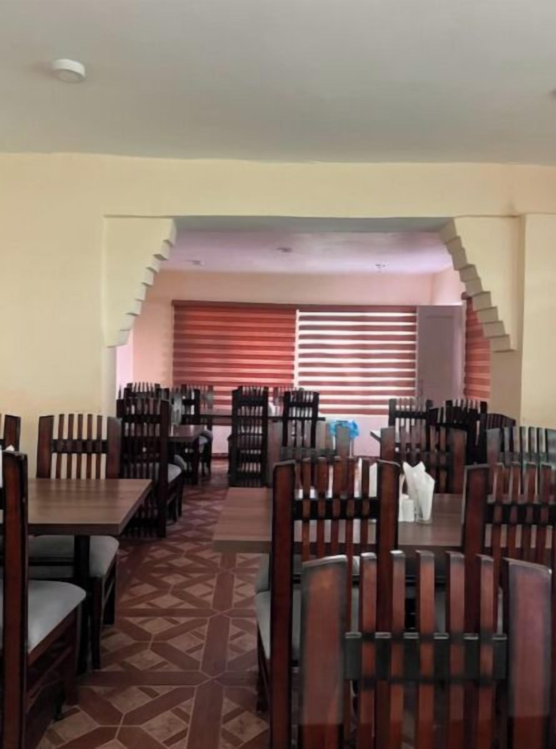 A dining area with multiple tables and chairs, a patterned floor, and a window with blinds.