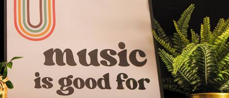 Un cartel con el texto 'music is good for the soul' y una planta de helecho en una maceta.