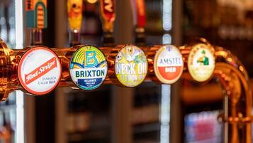 Una hilera de grifos de cerveza con etiquetas para Red Stripe, Brixton, Necks Oil y Amstel.