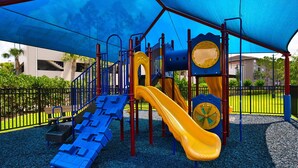 Une aire de jeux avec un toboggan, des structures d’escalade et un espace abrité.