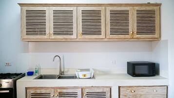 A kitchen with wooden cabinets, a stainless steel sink, a microwave, and a gas stove.