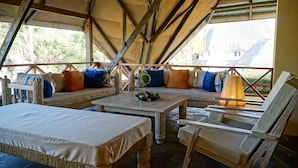 A cozy, open-air lounge with a wooden bench, a table, and a chair. - Relaxing Beach Front Villa (Malindi)