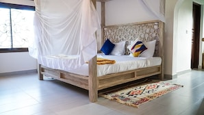 A four-poster bed with a canopy, a patterned headboard, and a colorful throw blanket. - Relaxing Beach Front Villa (Malindi)