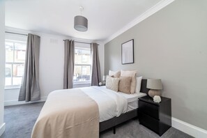 Une chambre à coucher avec un lit, une table de chevet et une fenêtre avec des rideaux.