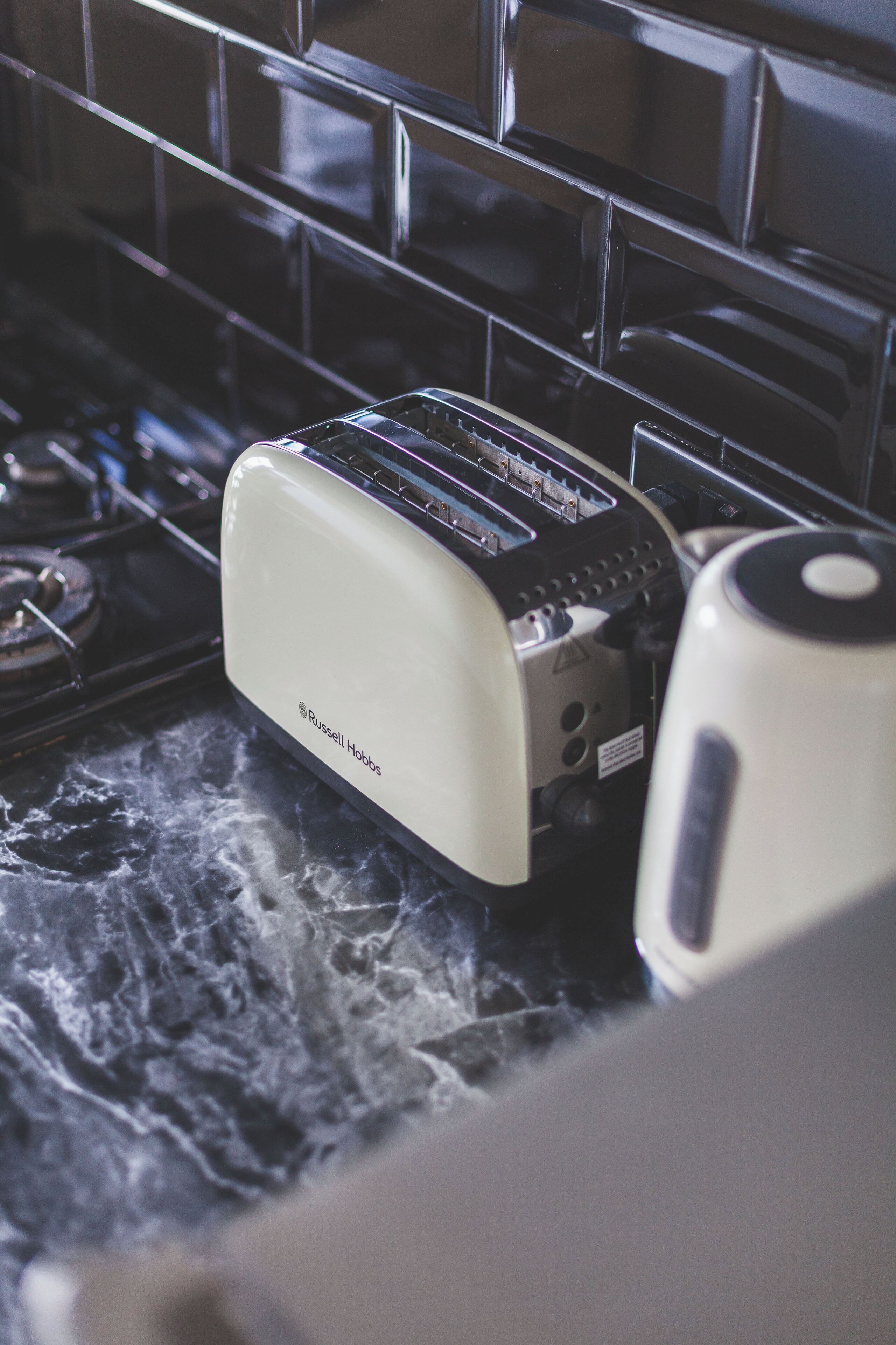 A kitchen with a toaster and a kettle on a marble countertop.