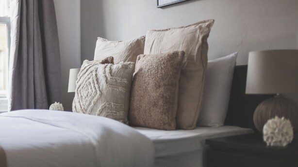 A neatly made bed with multiple pillows and a bedside lamp. - The Peckham Luxury Apartment (London)