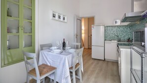 A compact kitchen with a dining area, white cabinetry, and a green-framed door. - Synagogue Suite (Florence)