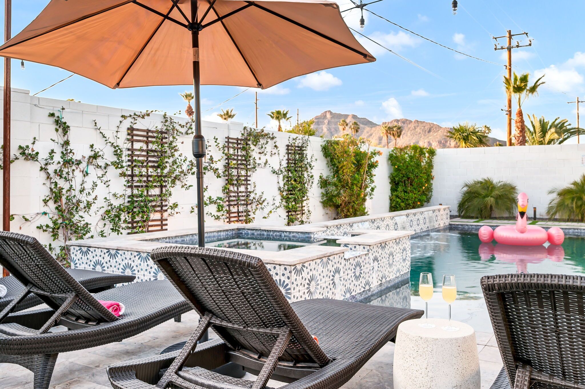 Un espace aménagé au bord de la piscine, avec des chaises longues, un grand parasol et un flotteur décoratif en forme de flamant rose.