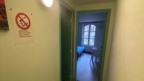 Un pasillo estrecho con un cartel que prohíbe fumar y el uso de cigarrillos electrónicos.