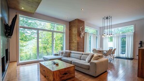 Un salon spacieux avec un grand canapé d’angle, une table basse en bois et une cheminée en pierre.