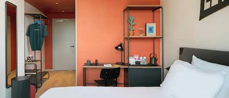 A hotel room with a bed, desk, chair, and a wardrobe.