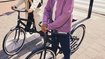 Two people standing next to bicycles on a sidewalk.