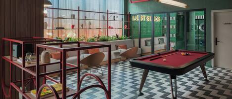 A pool table, seating area, and a laundry room in a modern interior.