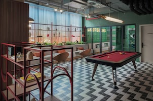 A pool table, seating area, and a laundry room in a modern interior.