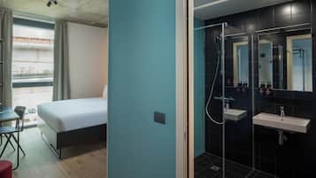 Une chambre d’hôtel moderne équipée d’un lit, d’un bureau et d’un espace douche.