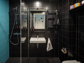 Et moderne badeværelse med en glasafskærmet brusekabine, et håndvask og en håndklædestang.