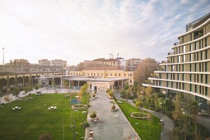 A courtyard with a central pathway, surrounded by greenery and outdoor seating.