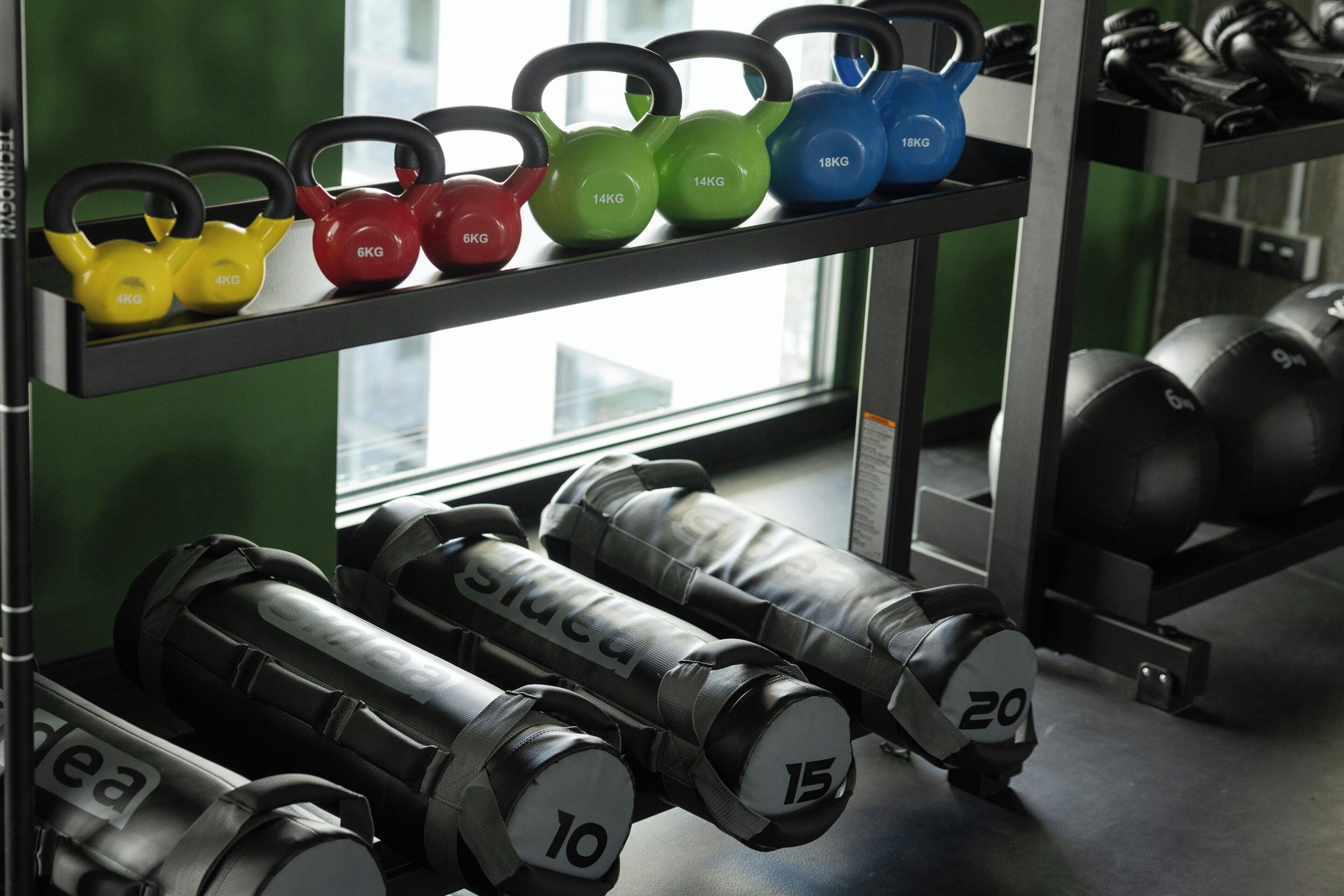 Kettlebells und Kurzhanteln auf einem Gestell im Fitnessstudio.