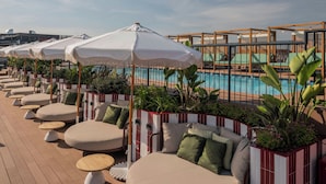 Ein Poolbereich mit Liegestühlen, Sonnenschirmen und einem Pool.