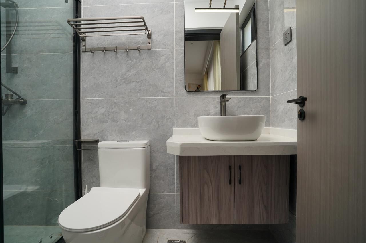 Un baño moderno con inodoro, lavamanos y espejo.