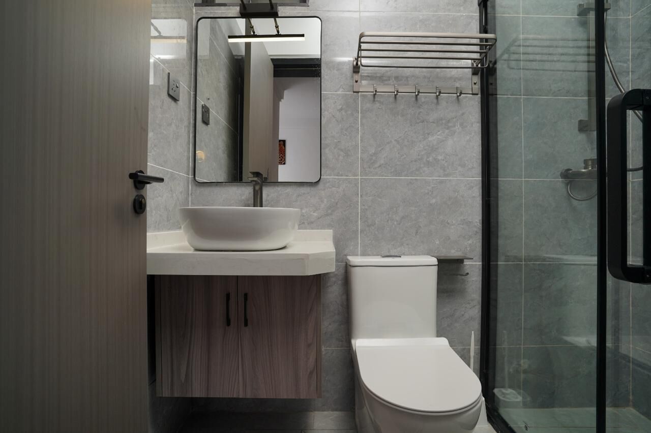 Un baño moderno con lavamanos, espejo y retrete blancos.
