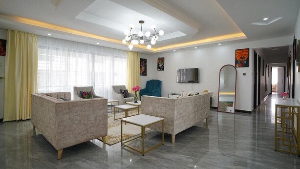 A modern living room with a sofa set, a TV, and a chandelier. - Lux Suites Platinum Oak Residency (Nairobi)