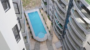 A modern multi-story building with a central swimming pool surrounded by balconies. - Lux Suites Platinum Oak Residency (Nairobi)