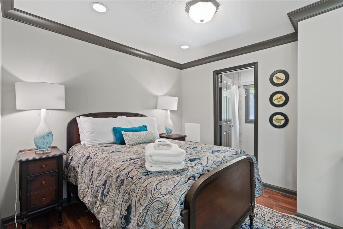 A bedroom with a bed, two bedside tables, lamps, a mirror, and wall-mounted bird decorations.