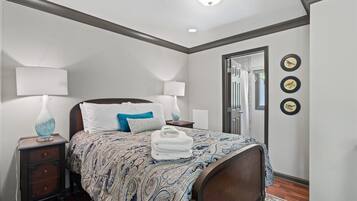 A bedroom with a bed, two bedside tables, lamps, a mirror, and wall-mounted bird decorations.