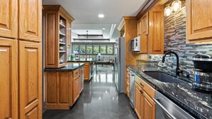 Una cocina moderna con armarios de madera, encimera negra y pileta de acero inoxidable.