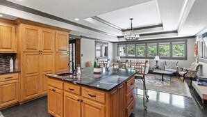 Una cocina amplia con armarios de madera, una isla de mármol y un comedor con sillas y un sofá.