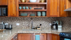 A kitchen with wooden cabinets, a granite countertop, a sink, a coffee maker, and a stove. - Sunny Days Villa At Playa Hermosa (Playa Hermosa)