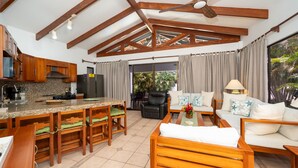 A spacious kitchen with wooden beams, a dining area with a table and chairs, and a living area with a sofa and a coffee table. - Sunny Days Villa At Playa Hermosa (Playa Hermosa)