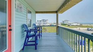 Een overdekt terras met uitzicht op het strand, met een tafel en stoelen.