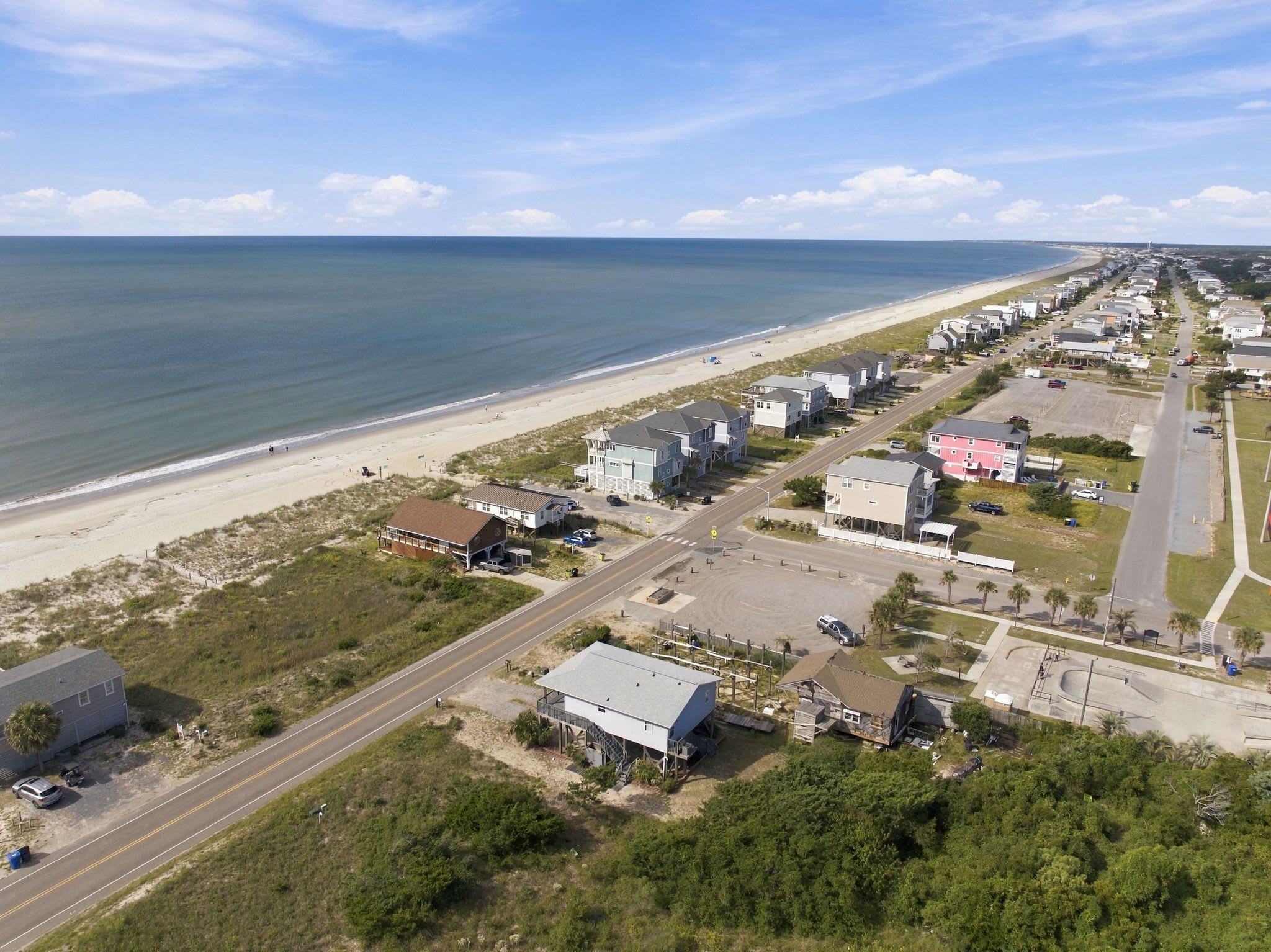 Un pueblo costero con playa, casas y una carretera.