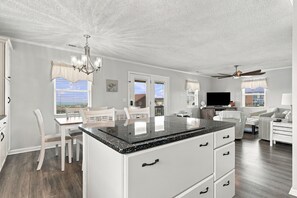 Een moderne keuken met een centraal eiland, witte kastjes en uitzicht op de omgeving.