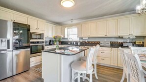 Een moderne keuken met witte kasten, roestvrijstalen apparatuur en een centraal keukenblok met zitplaatsen.