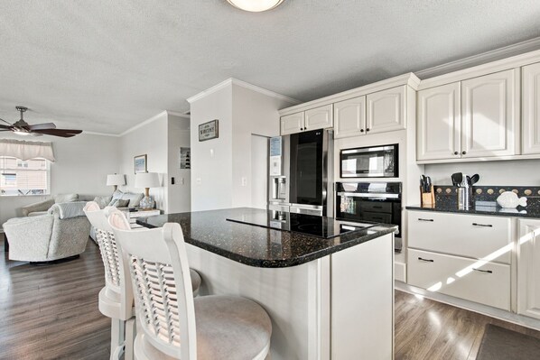 A modern kitchen with white cabinetry, a black granite countertop, and stainless steel appliances.